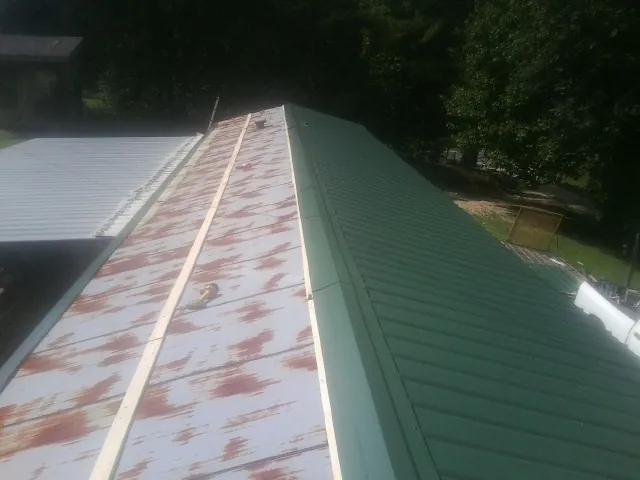 Old rusted panels beside newly installed green metal roofing — Wind Damage Roof Repair by Roofing Brothers in Charlotte